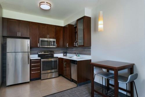 a kitchen with wooden cabinets and a table and a stove at Residence Inn by Marriott Omaha Aksarben Village in Omaha