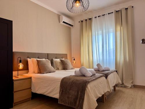 a bedroom with two beds and a large window at Cosy 1-Bedroom Apartment with Private Terrace in Loulé in Loulé