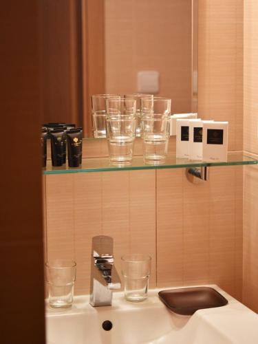 a counter with glasses on a shelf and a sink at Hotel Horník in Žďár nad Sázavou