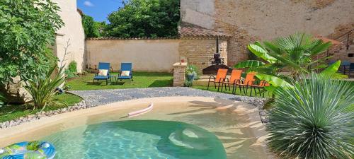 a swimming pool in a backyard with chairs and tables at La Belle Bourguignonne in Crêches-sur-Saône