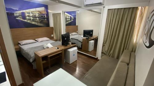 a bedroom with a bed and a couch and a mirror at UH 1205- 3 Pessoas e garagem S4 HOTEL in Águas Claras