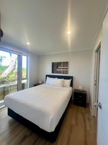 a bedroom with a large bed and a large window at Waipu Cove Surf Cabin in Waipu