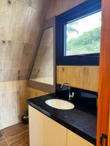 Un baño con lavabo y ventana. en Cabana Refúgio na Serra, en Santa Maria do Erval