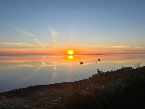 a sunset on a lake with boats in the water at Charming Retreat in Ringkobing - By Traum Ferienwohnungen in Ringkøbing