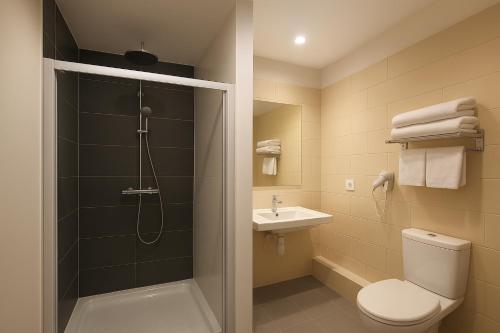 a bathroom with a shower and a toilet and a sink at GLASSY HOTEL, The Originals City, Marne-la-Vallée Est, Meaux in Meaux