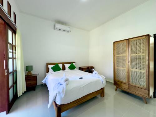 a white bedroom with a bed and a dresser at Bali Stuti Jimbaran Inn in Jimbaran