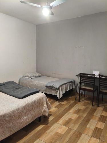 a room with two beds and a desk and a table at CASA sobrado edícula aconchegante in São Paulo