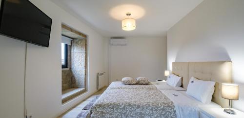 a bedroom with a bed and a flat screen tv at Casa do Barroso - Casa Mãe in Cabeceiras de Basto