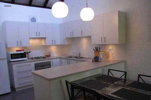 uma cozinha com armários brancos e uma mesa com cadeiras em Kenata-Fairway em Perth