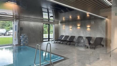 Zimmer mit einem Pool mit Stühlen und einem Tisch in der Unterkunft Omega Lake Apartments Nr 60 in Olsztyn