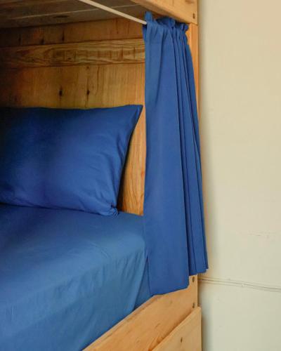 a wooden bunk bed with blue sheets and a blue pillow at El Pinche Hostal in Guadalajara