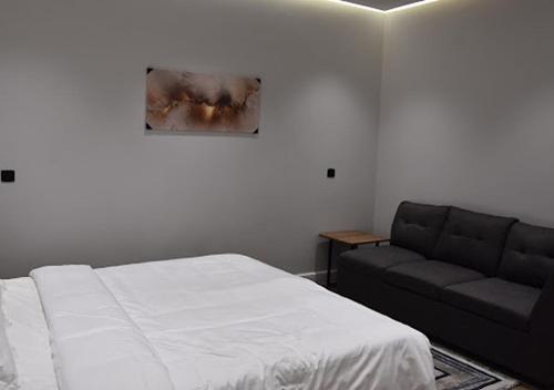 a bedroom with a bed and a couch at شقه فرح Farah Apartment in Hail