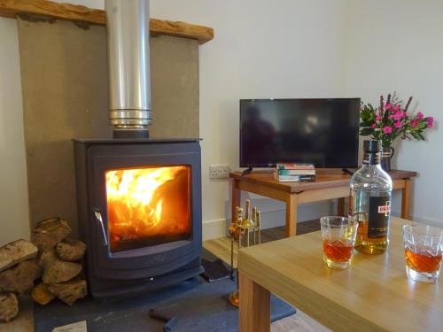 einen Holzofen im Wohnzimmer mit einem Tisch in der Unterkunft Charlies Cottage in Muasdale