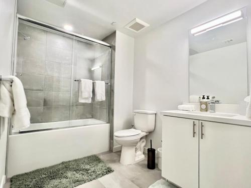 a white bathroom with a shower toilet and a sink at Designer 1 Bedroom Condo in Silver Lake in Los Angeles