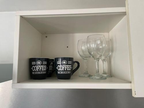 two cups and two wine glasses sitting on a shelf at Elegant studio in Arcueil