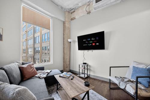 Una sala de estar con un sofá y un televisor en una pared. en Stunning Downtown Apartment with Pool, Laundry, Parking, en Dallas