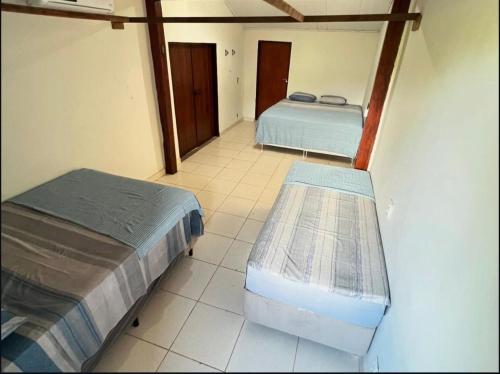 two beds sitting in a room with a tiled floor at Casa Tropical in Marau