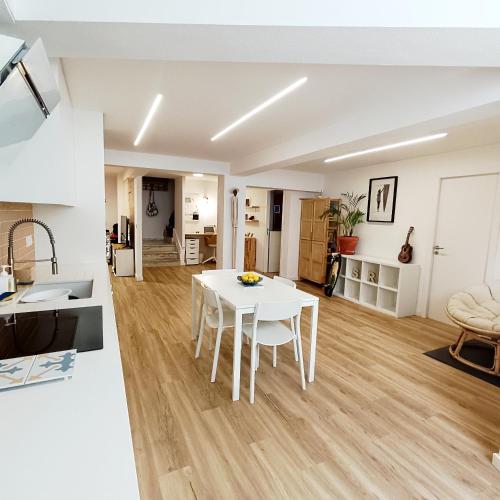 a kitchen and a living room with a white table at SUPERTUBOS HOUSE Peniche in Peniche