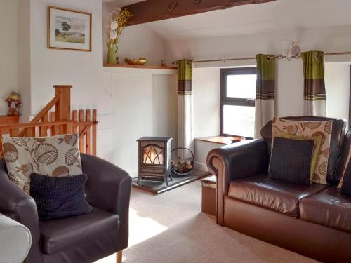 a living room with a couch and a chair and a wood stove at Greystones Cottage in Hardraw