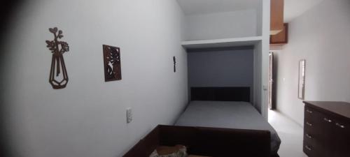 a bedroom with a bed in a white wall at Kitnet Sossego na Praia (Caraguatatuba/Massaguaçu) in Caraguatatuba