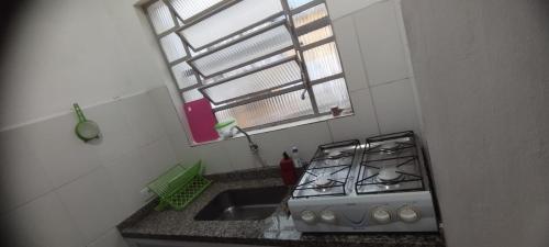 a kitchen with a stove and a sink and a window at Kitnet Sossego na Praia (Caraguatatuba/Massaguaçu) in Caraguatatuba