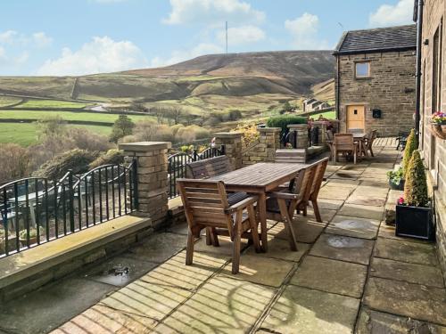 a wooden table and chairs on a patio with a view at Trough Cottage - Uk48424 in Holmfirth