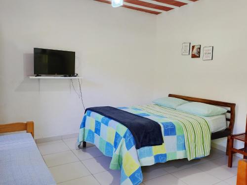 a bedroom with a bed and a flat screen tv at Kitnet da Adriana in Paraty