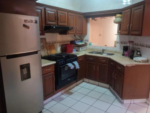 a kitchen with wooden cabinets and a black stove at Private room with WiFi TV y Aire acondicionado in Los Mochis