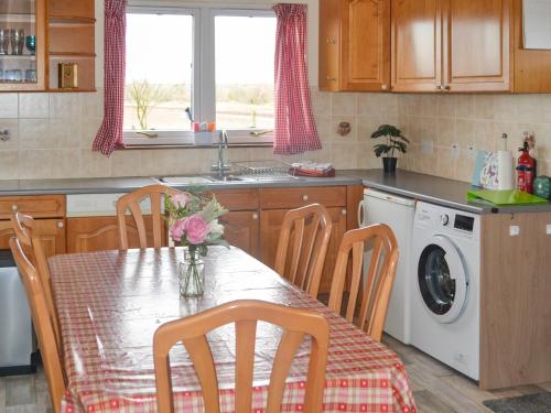 a kitchen with a table with a vase of flowers on it at The Junipers in Tain