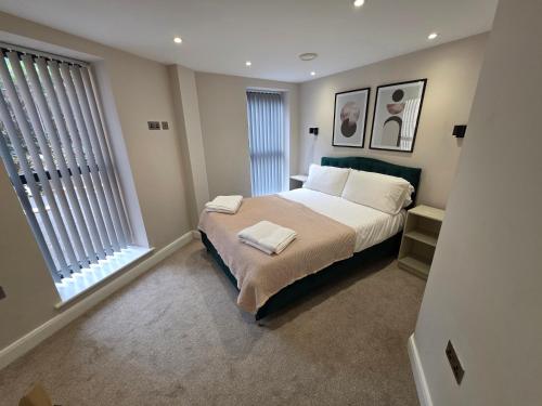 a bedroom with a large bed and two windows at Cosy Leeds City Centre Apartment in Central Station
