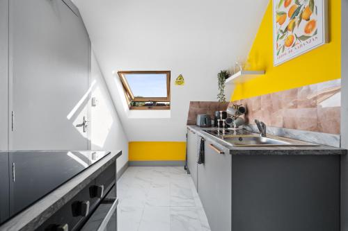 a kitchen with yellow and white walls and a sink at The Cosy Place - BHX Airport, NEC, HS2 & RES World in Marston Green