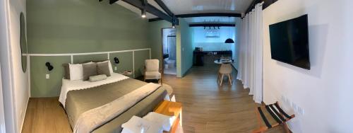 a bedroom with a bed and a living room at Bangalô 2 Rota do Vinho São Roque in São Roque