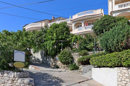 a building on a hill with trees and a street at Apartments with parking space Lopar, Rab - 24617 in Lopar