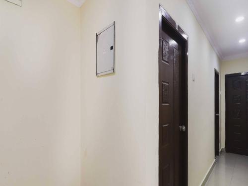 a hallway with a black door and a white wall at Hotel O Sai Pariwar in Vidya Nagar