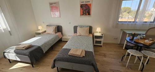two beds in a room with a table and a tableablish at Ideal Bubble House in Faro