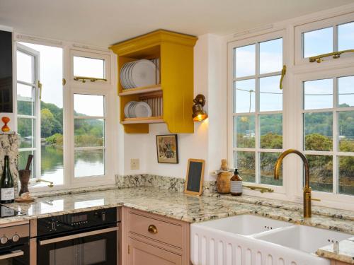 a kitchen with yellow cabinets and windows and a sink at Island House in Fowey