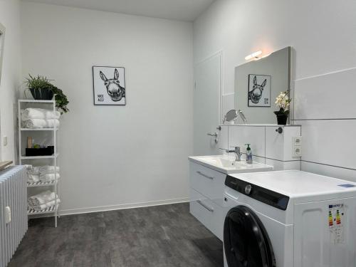 ein weißes Badezimmer mit einem Waschbecken und einer Waschmaschine in der Unterkunft Come Stay Relax Apartment für bis zu 6 Personen - Parkplatz - WLAN - Homeoffice in Trier