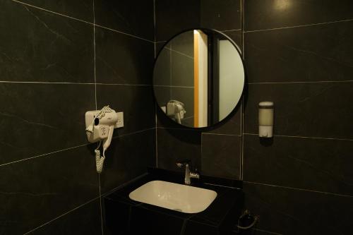 a black tiled bathroom with a sink and a mirror at Hanoi Wanderlust Hostel & Travel in Hanoi