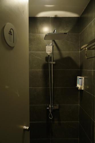 a bathroom with a shower with black tiles at Hanoi Wanderlust Hostel & Travel in Hanoi