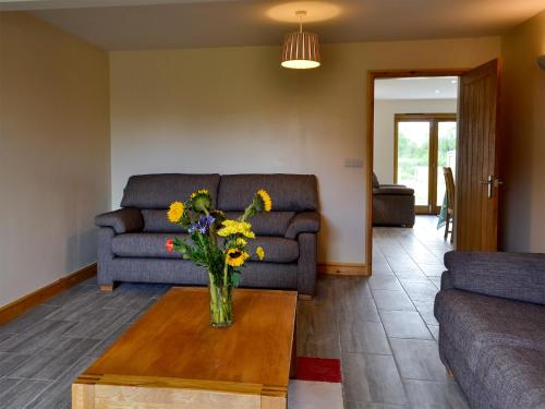 ein Wohnzimmer mit einem Sofa und einer Vase mit Blumen auf dem Tisch in der Unterkunft 4 Greenhaye Cottages - Uk31236 in Newnham
