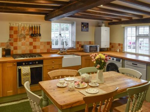 a kitchen with a wooden table with flowers on it at Rose Cottage in Bethersden