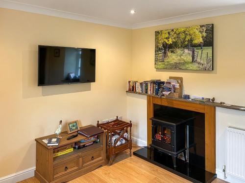 a living room with a fireplace and a flat screen tv at River View Pateley - Uk47337 in Pateley Bridge