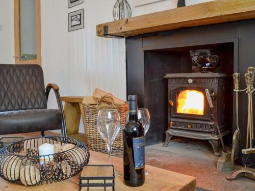 a bottle of wine sitting on a table in front of a fireplace at Black Spout Cottage in Moulin