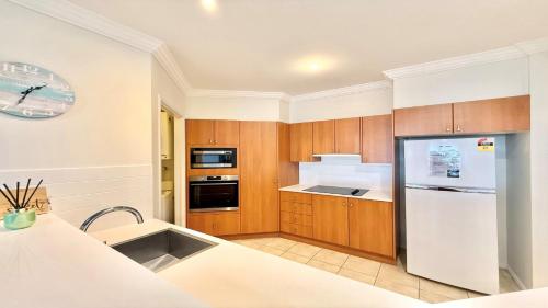 a kitchen with wooden cabinets and a white refrigerator at Breakers 2 - 7, 18 - 20 Pacific Parade in Yamba