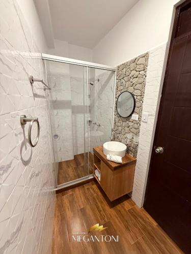 a bathroom with a shower with a sink and a mirror at Grand Hotel Megantoni in Quillabamba