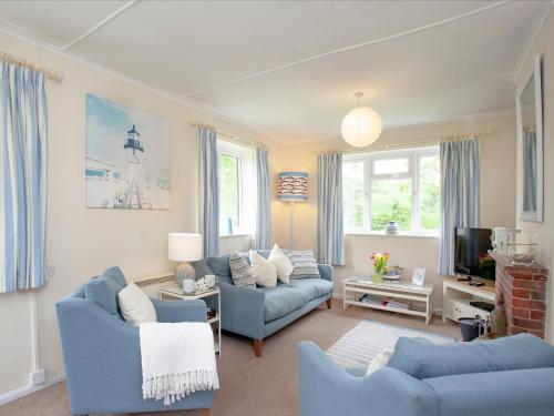 Una sala de estar con dos sofás azules y un televisor. en Sweet's Close, en St Austell