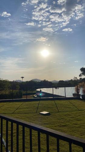 a view of a field with a fence and the sun at QUINTA santa BÁRBARA RESORT in Pirenópolis