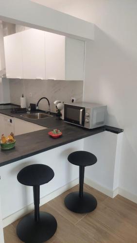 a kitchen with two black stools in front of a counter at RIVER VIEW TMB oporto station house in Porto