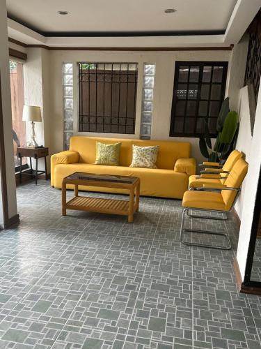 a living room with a yellow couch and two chairs at Subic Bay Baloy Long Beach Hotel in Olongapo