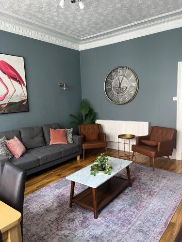 a living room with a couch and a clock on the wall at 3BR Apt Near Ibrox Subway Sleeps 7 and Parking in Glasgow